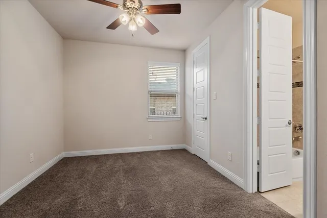 an empty room with chandelier fan and windows
