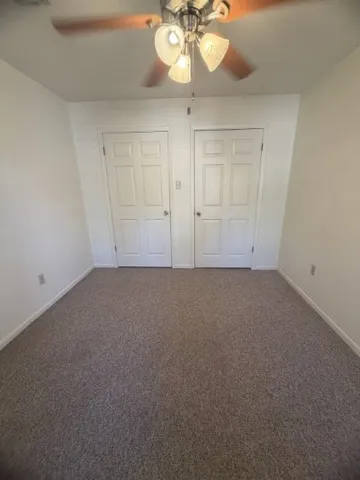 a view of an empty room and a chandelier fan