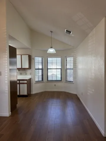a view of an empty room with a window and wooden floor