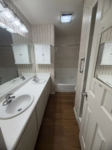 a bathroom with a double vanity sink a mirror and a bathtub