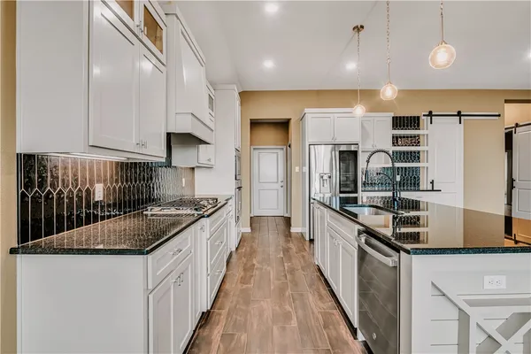 a kitchen with stainless steel appliances granite countertop a stove a sink and a refrigerator