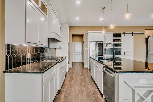 a kitchen with stainless steel appliances granite countertop a stove a sink and a refrigerator