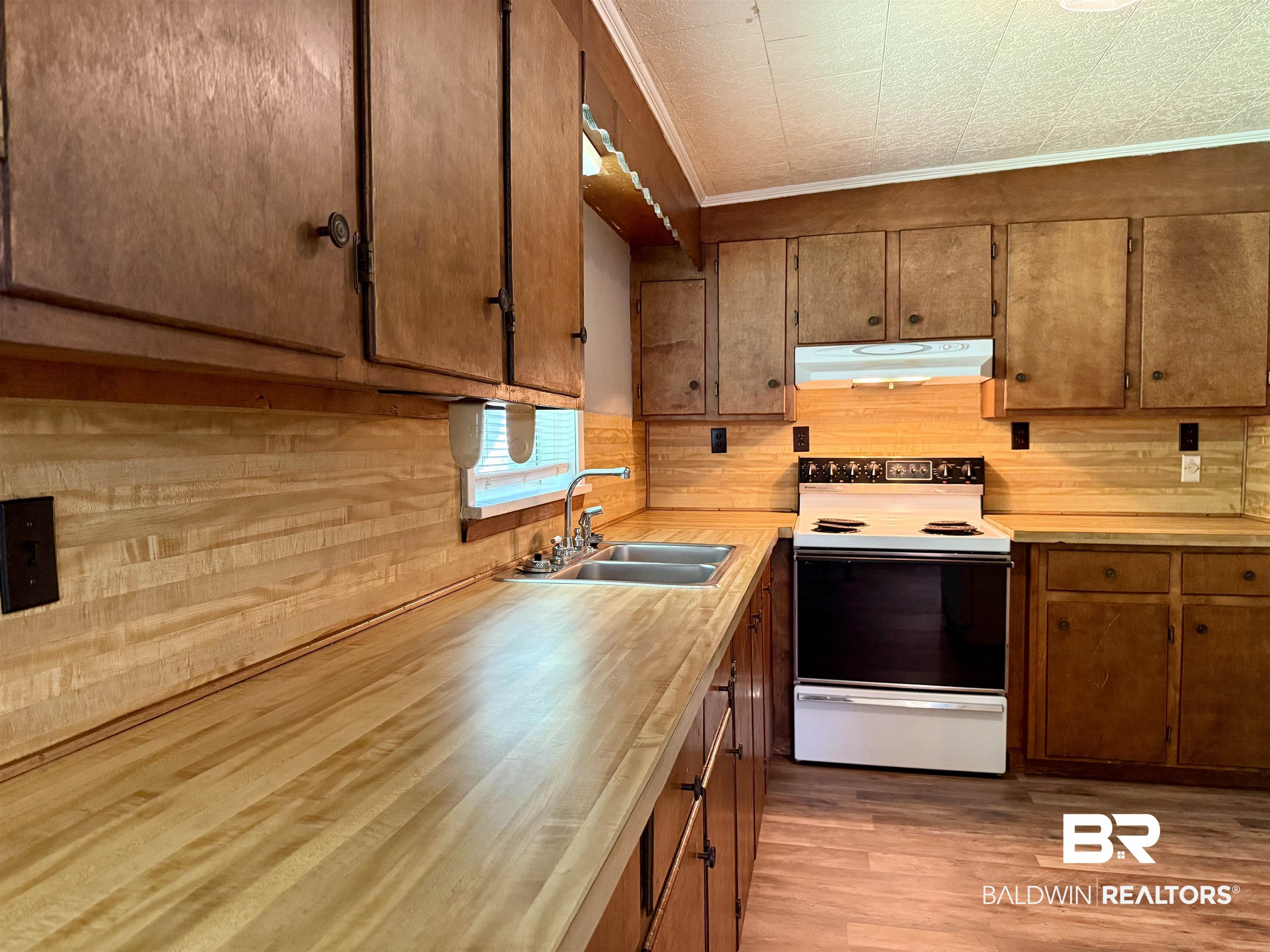 103 Kimberly Street Brewton, AL 36426 - Photo 7 of 18 Kitchen with electric range, under cabinet range hood, light countertops, crown molding, and light wood-style flooring