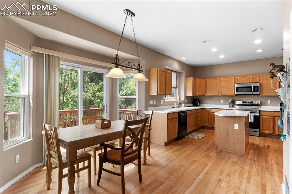 803 Ridgebury Place Fountain, CO 80817 - Photo 17 of 45 a kitchen with stainless steel appliances granite countertop a stove top oven a sink dishwasher a dining table and chairs with wooden floor