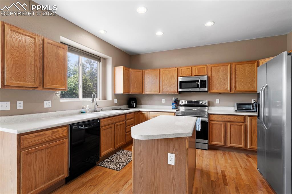 803 Ridgebury Place Fountain, CO 80817 - Photo 20 of 45 a kitchen with stainless steel appliances granite countertop a stove top oven a sink dishwasher a refrigerator and cabinets with wooden floor