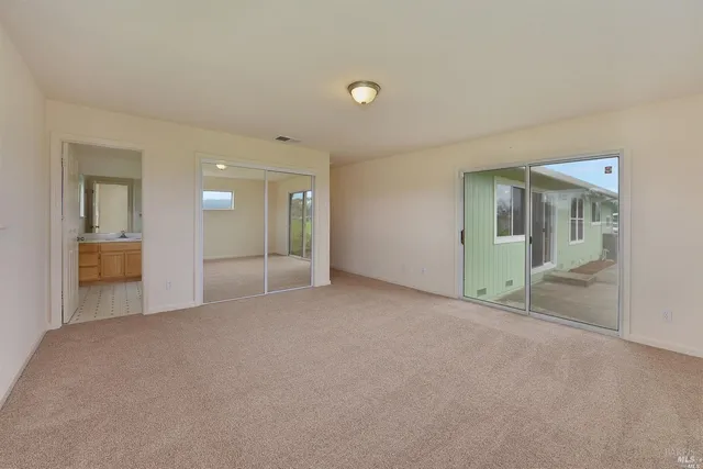 an empty room with window and a kitchen