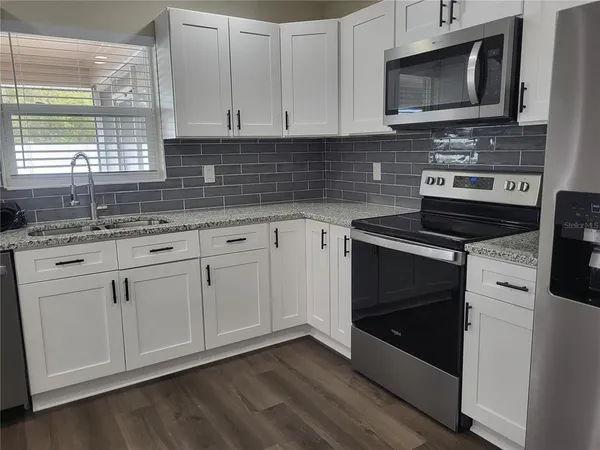 a kitchen with white cabinets and appliances