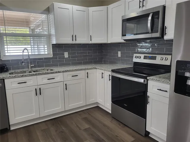 a kitchen with white cabinets and appliances