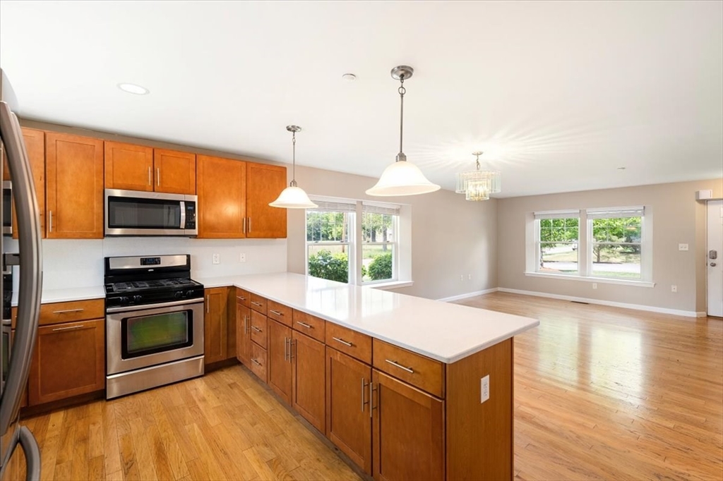 6 Bates Street, Unit A Devens, MA 01434 - Photo 17 of 41 a kitchen with stainless steel appliances granite countertop a sink a stove and a wooden floors