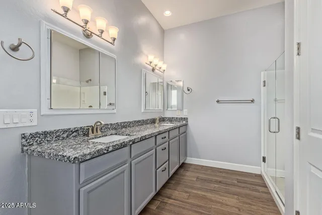a bathroom with a granite countertop sink a large mirror and a shower