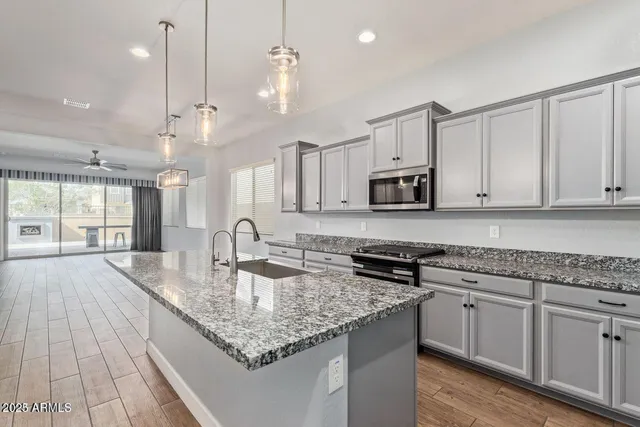a kitchen with granite countertop a sink a counter space appliances and cabinets