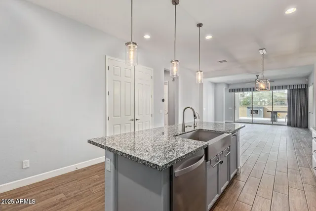 a kitchen with stainless steel appliances granite countertop a sink a center island and a wooden floor