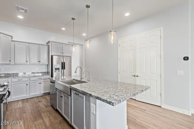 a kitchen with stainless steel appliances granite countertop a sink refrigerator and cabinets
