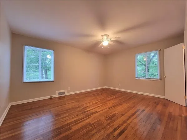 an empty room with wooden floor and windows