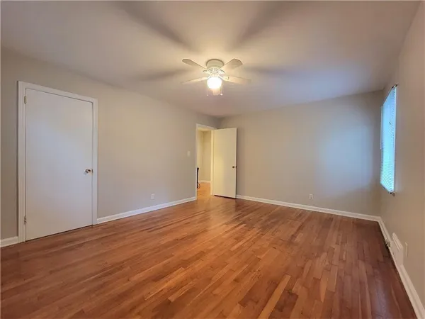 a view of empty room with wooden floor and fan