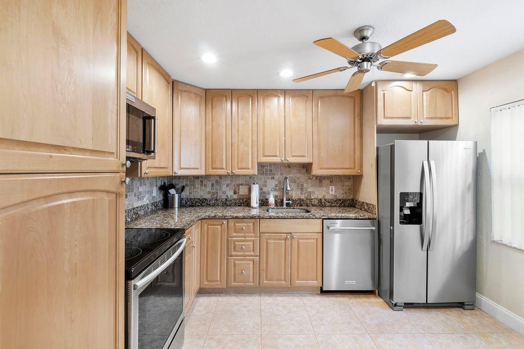 21452 Juego Circle, Unit 31A Boca Raton, FL 33433 - Photo 9 of 38 a kitchen with stainless steel appliances granite countertop a stove a sink and a refrigerator