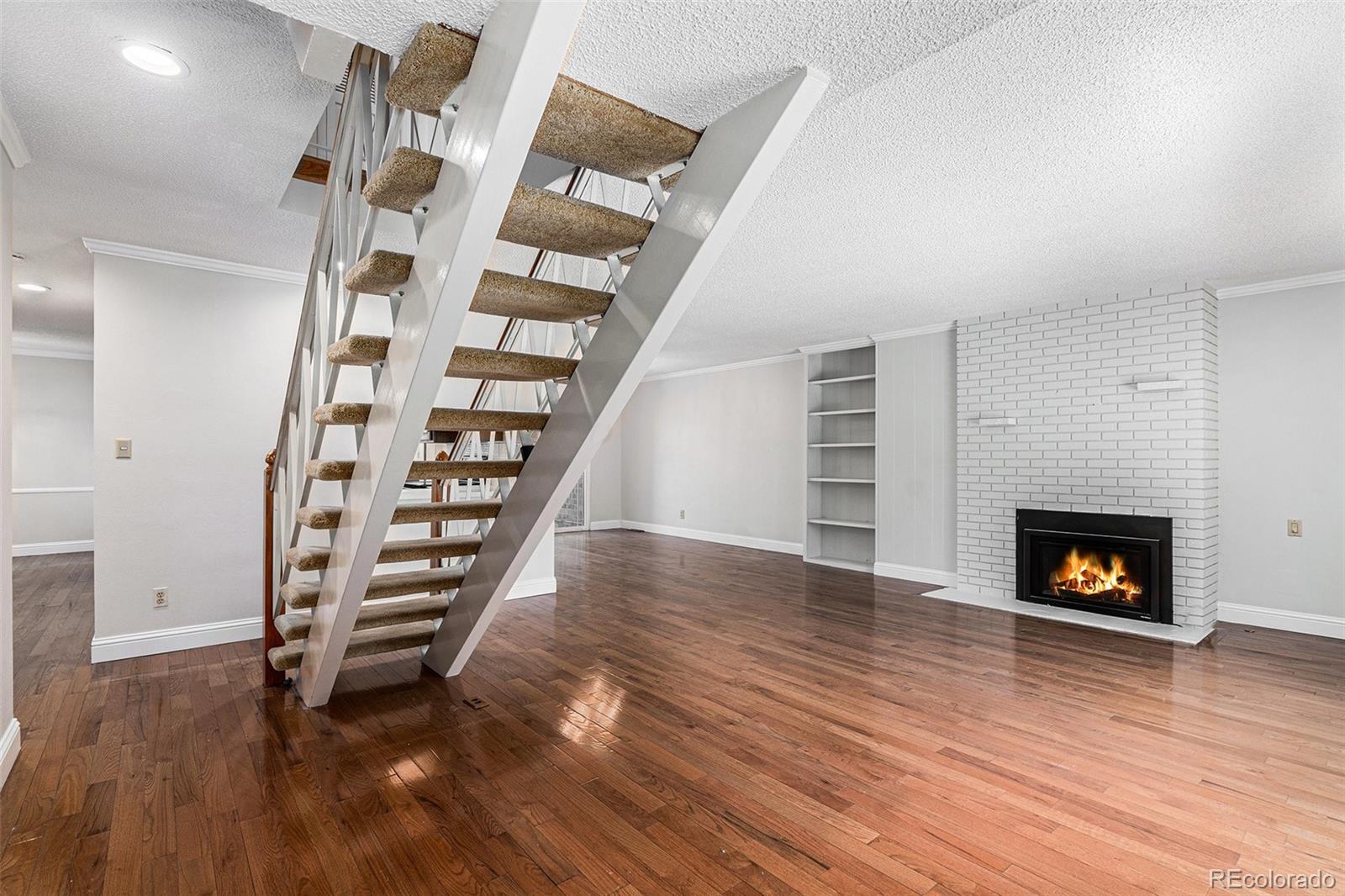 3210 South Oneida Way Denver, CO 80224 - Photo 5 of 28 an empty room with wooden floor and a fireplace