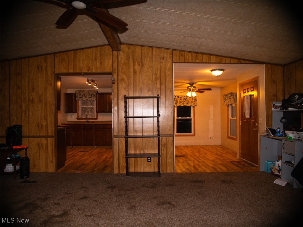 332 Max Road Lodi, OH 44254 - Photo 4 of 22 Unfurnished living room featuring ceiling fan, lofted ceiling with beams, wood-type flooring, and wood walls