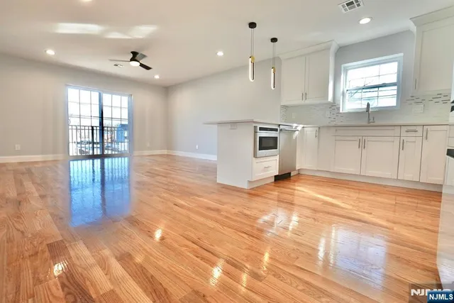 a view of a kitchen with kitchen island a sink wooden floor and stainless steel appliances
