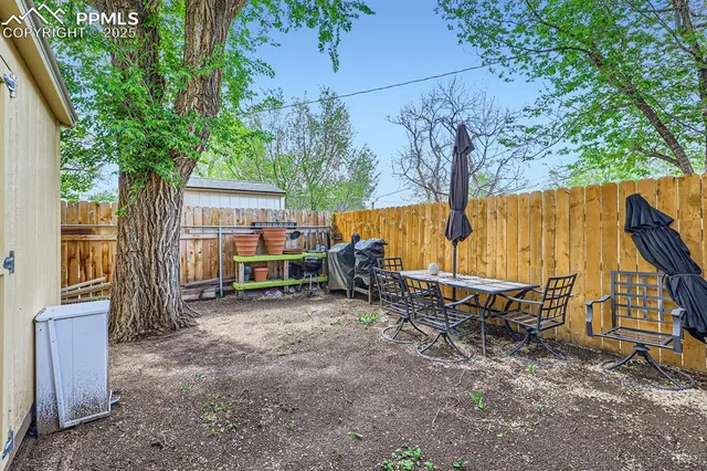 a view of backyard with a table and chairs and a large tree