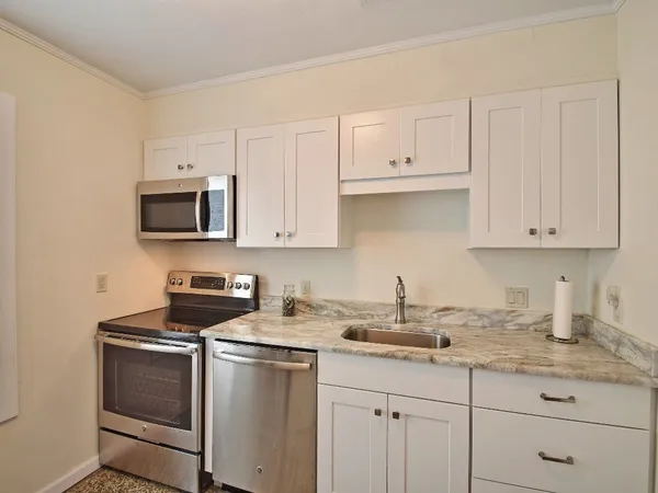 a kitchen with granite countertop white cabinets sink and stainless steel appliances