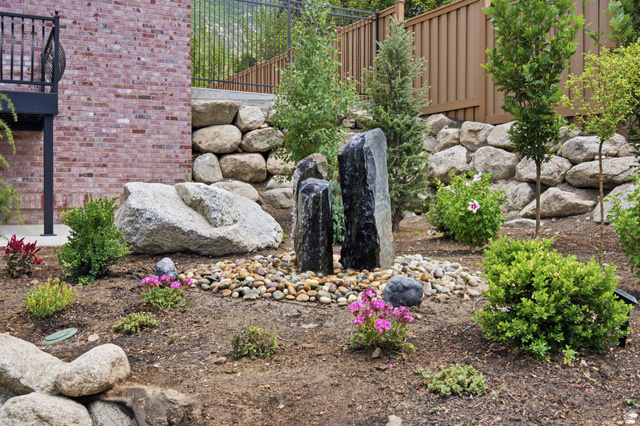 12308 Mariah Circle Draper, UT 84020 - Photo 241 of 293 Guest House Landscaped terraced yard featuring a multi-column water feature with a pebble surround, retaining walls, mature plantings, and a red brick exterior