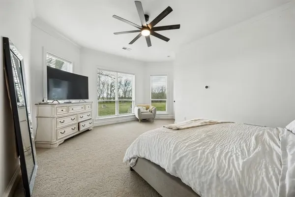 a bedroom with a large bed and a flat tv screen on dresser