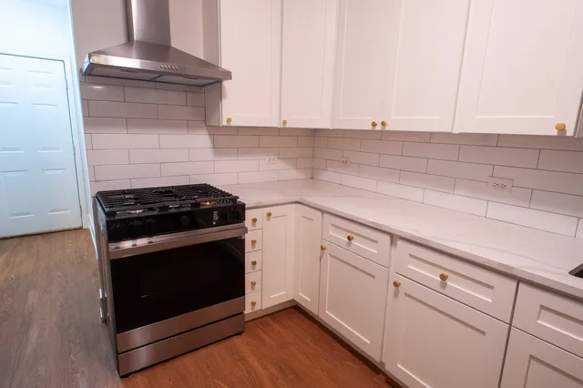 a kitchen with granite countertop a stove and a white cabinets