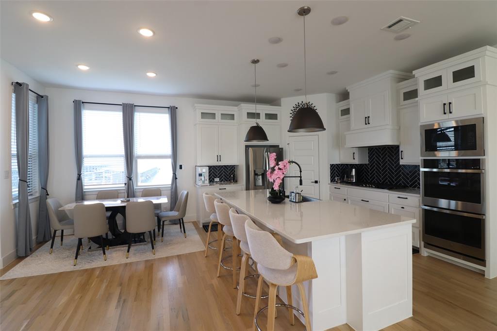 1205 Marc Place Rowlett, TX 75088 - Photo 14 of 30 a kitchen that has a table chairs in it and wooden floors
