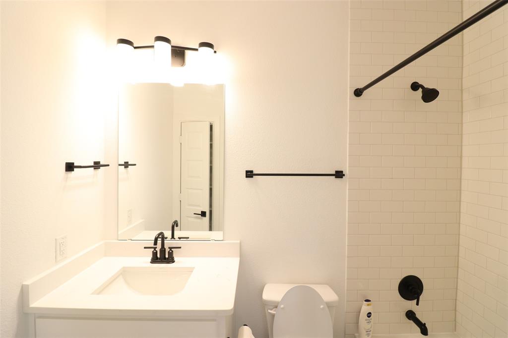 1205 Marc Place Rowlett, TX 75088 - Photo 5 of 30 a bathroom with a sink a toilet and a mirror