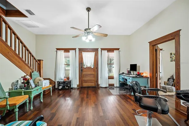 a living room with furniture floor to ceiling window hardwood floor and a ceiling fan