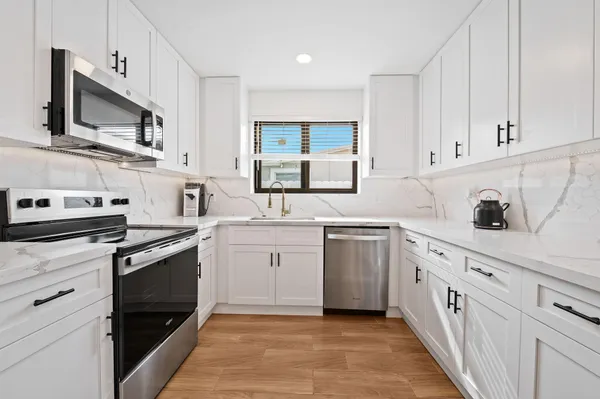 a kitchen with white cabinets appliances and a sink