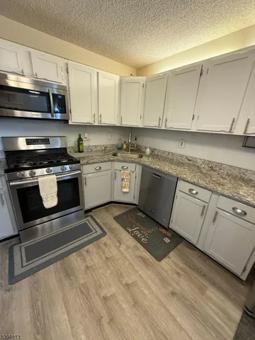 a kitchen with stainless steel appliances granite countertop a refrigerator a stove and a sink