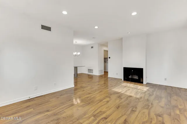 a view of an empty room with window and wooden floor
