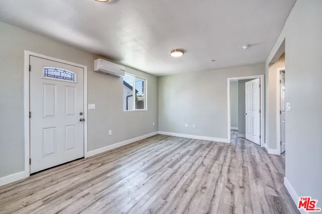 a view of an empty room with wooden floor and a window