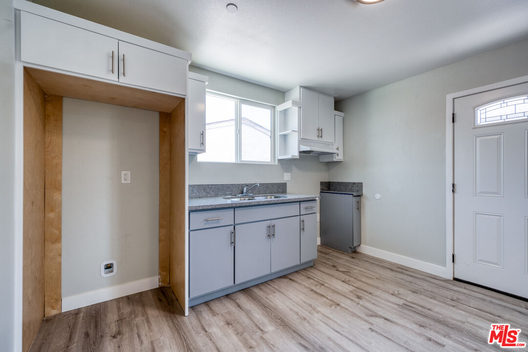 1947 East 114th Street, Unit 1947 1/2 Los Angeles, CA 90059 - Photo 8 of 16 a kitchen with granite countertop white cabinets and white appliances