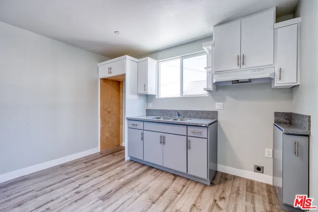 a kitchen with granite countertop wooden cabinets and a wooden floor