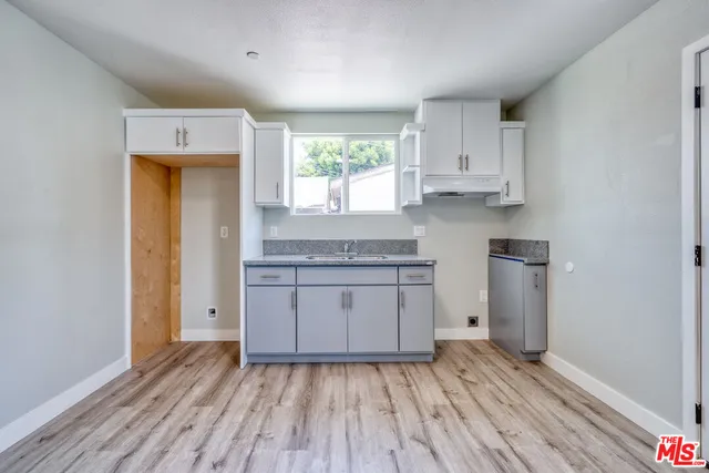 a kitchen with wooden floors and white cabinets