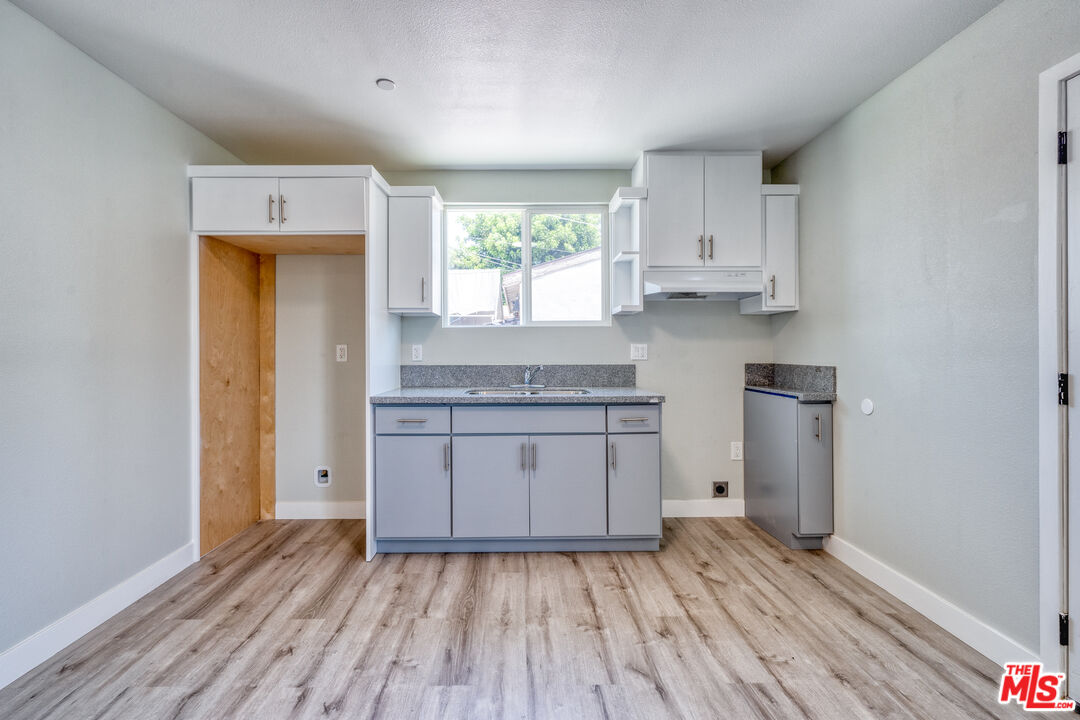 1947 East 114th Street, Unit 1947 1/2 Los Angeles, CA 90059 - Photo 10 of 16 a kitchen with wooden floors and white cabinets