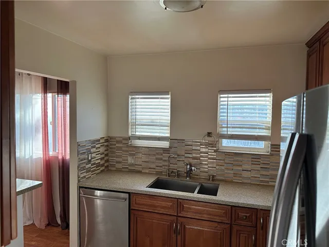 a kitchen with stainless steel appliances granite countertop a sink and a refrigerator