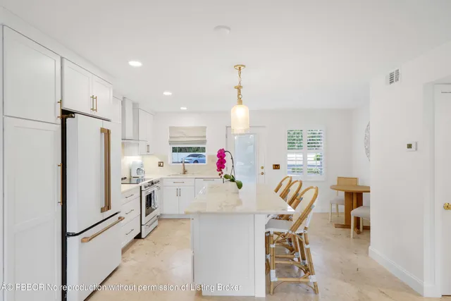 a kitchen with stainless steel appliances kitchen island granite countertop a refrigerator and a dining table