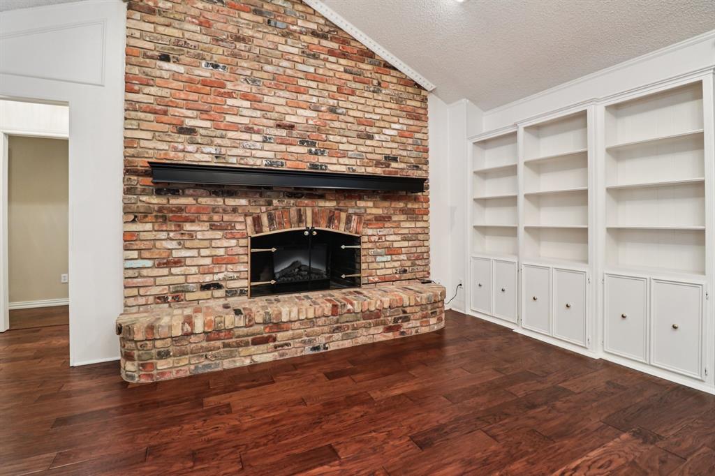 1015 Crowley Road Arlington, TX 76012 - Photo 10 of 36 a living room with a fireplace a flat screen tv and a wooden floor