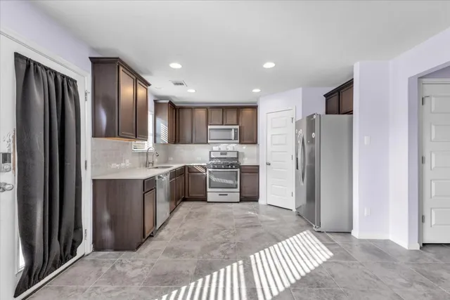 a kitchen with granite countertop a refrigerator and a stove top oven