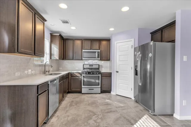 a kitchen with stainless steel appliances granite countertop a refrigerator and a sink