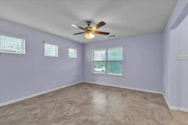 an empty room with windows and fan
