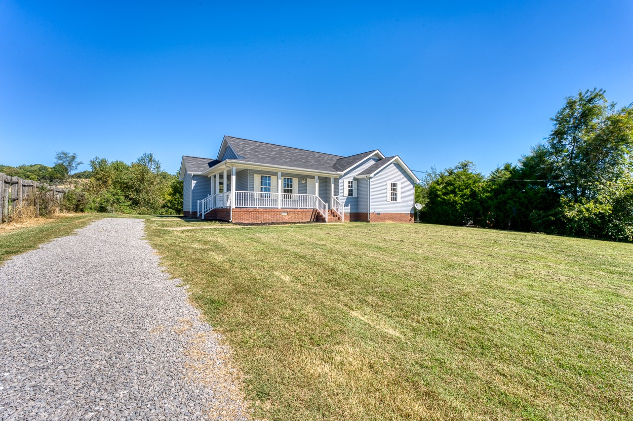 a view of house with yard and trees in the background