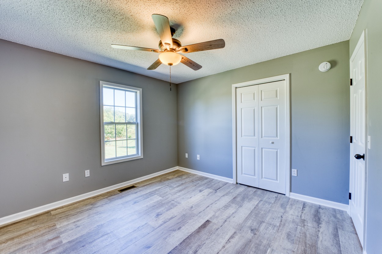 1464 Little Dry Creek Road Pulaski, TN 38478 - Photo 17 of 26 an empty room with wooden floor fan and windows