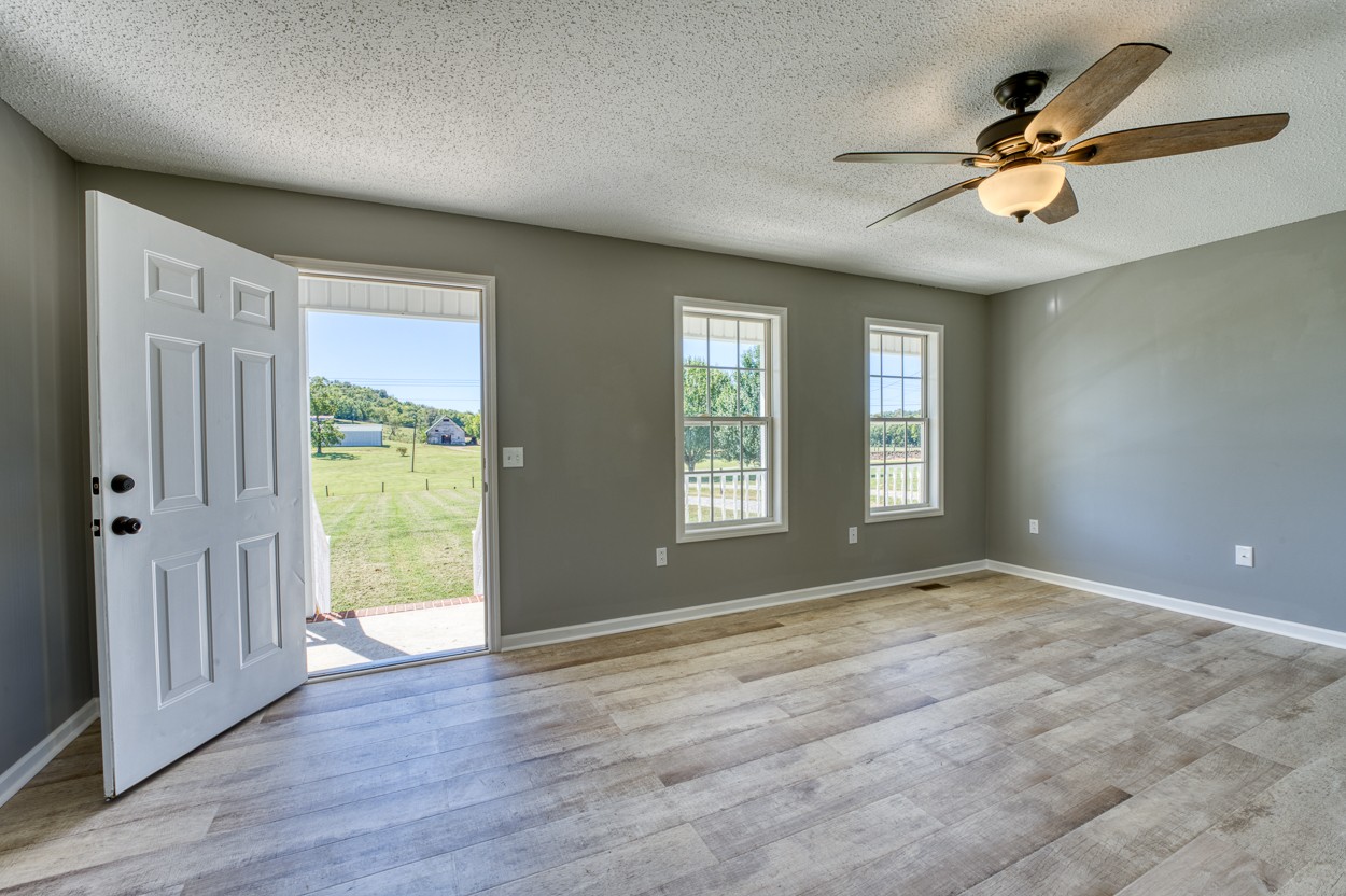 1464 Little Dry Creek Road Pulaski, TN 38478 - Photo 6 of 26 an empty room with wooden floor fan and windows
