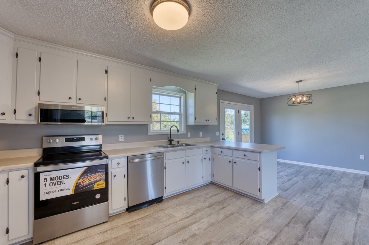 1464 Little Dry Creek Road Pulaski, TN 38478 - Photo 7 of 26 a kitchen with stainless steel appliances granite countertop a stove a sink and white cabinets