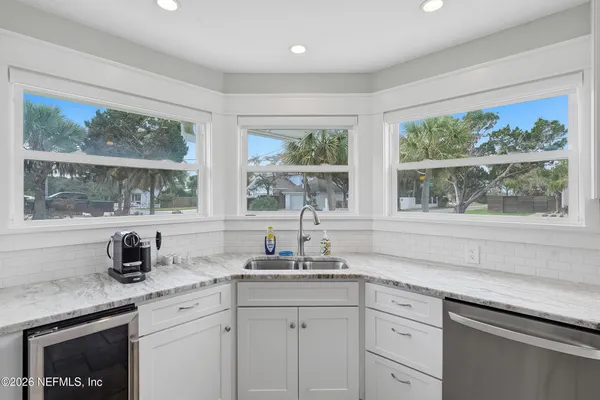 a kitchen with stainless steel appliances granite countertop white cabinets and a large window